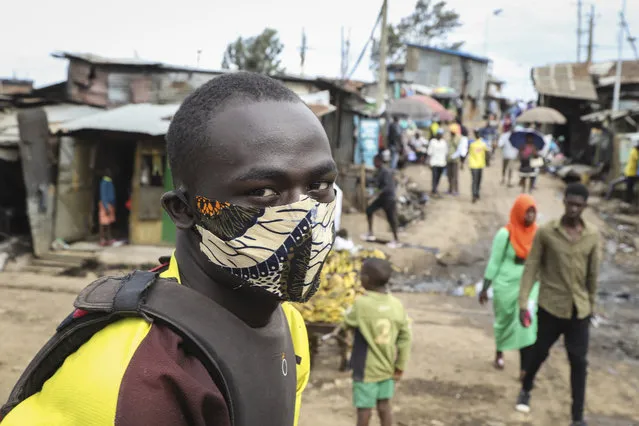 A boda-boda, or motorcycle taxi, driver wears a makeshift mask made from a local fabric known as Kitenge as he looks for customers in the Kibera neighbourhood of Nairobi, Kenya Friday, March 20, 2020. (Photo by Patrick Ngugi/AP Photo)
