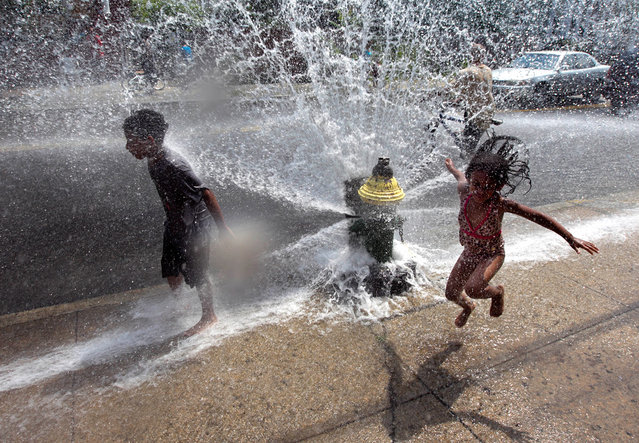 Four-year-old Solaris Arias (right) jumps through water spraying from an open fire hydrant in Providence, Rhode Island, on June 20, 2012. Much of the state remained under a heat advisory Tuesday afternoon because of the steamy air mass that has moved into the region resulting in temperatures in the 90s. (Photo by Steven Senne/AP Photo)