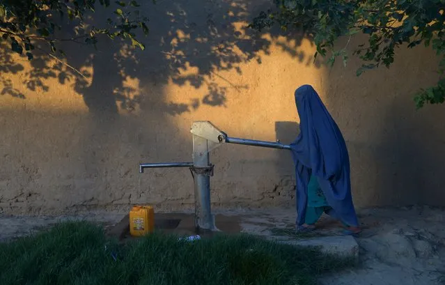 In this photograph taken on June 30, 2017 an Afghan woman collects water from a hand pump in Mazar-i-Sharif in Ghazni province. (Photo by Farshad Usyan/AFP Photo)