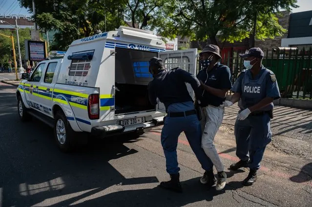 South African Police Service (SAPS) officers leads a man to the back of a police vehicle in Sunnyside, Pretoria, on May 7, 2020, during a joint patrol of the South African National Defence Force (SANDF), the South African Police Service (SAPS) and the Tshwane Metro Police Department (TMPD) to enforce level 4 lockdown regulations to help curb the spread of the COVID-19 coronavirus. (Photo by Christiaan Kotze/AFP Photo)