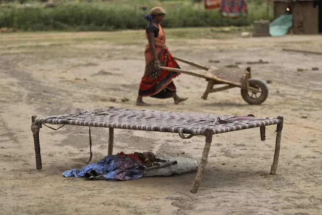 An Indian woman works at a brick kiln as her child sleeps under a cot during lockdown to curb the spread of new coronavirus on the outskirts of Jammu, India, Sunday, May 10, 2020. (Photo by Channi Anand/AP Photo)