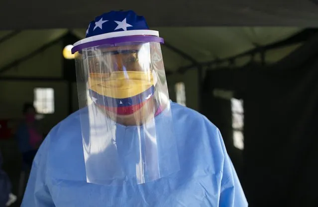 Wearing a mask decorated with the colors of the Venezuelan flag, and a face shield, Hospital Director Dr. Zaira Medina, stands in a tent set up at the entrance of the Ana Francisca Perez de Leon Hospital as she oversees the employment of fast testing for coronavirus in Caracas, Venezuela, Wednesday, April 15, 2020. Venezuela is going about testing its citizens unlike any other country: Mass deployment of a rapid blood antibody test from China that checks for proteins that develop a week or more after someone is infected, while using on a much smaller scale the gold-standard nasal swab exam that detects the virus from the onset. (Photo by Ariana Cubillos/AP Photo)