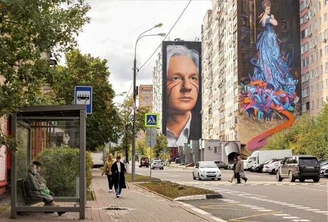 People walk along the street with the murals on display on multi-storey apartment blocks during the international festival Urban Morphogenesis, held in the town of Balashikha outside Moscow, Russia on September 20, 2022. (Photo by Evgenia Novozhenina/Reuters)