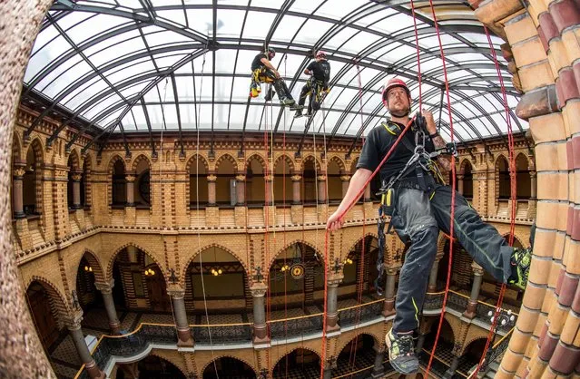 Industrial climber Andre Erdmann (R), manager of the company Special Rope Access, cleans the glass roof in the Staendehaus in Rostock, Germany, 09 August 2016. The official residence of the Higher Regional Court (OLG) of the federal state of Mecklenburg-Western Pomerania was built between 1889 and 1893 and elaborately restored several years ago. The glass roof of the heritage-protected neo-Gothic building has now been cleaned inside and out by the specialty firm for the first time. (Photo by Jens Buettner/EPA)