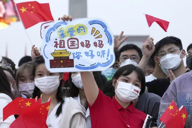 In this photo released by Xinhua News Agency, a woman holds up a card with the words “Dear Motherland, Hello!” as she attends the flag raising ceremony to mark the 73rd anniversary of the founding of the People's Republic of China held at the Tiananmen Square in Beijing on Saturday, October 1, 2022. (Photo by Ju Huanzong/Xinhua via AP Photo)