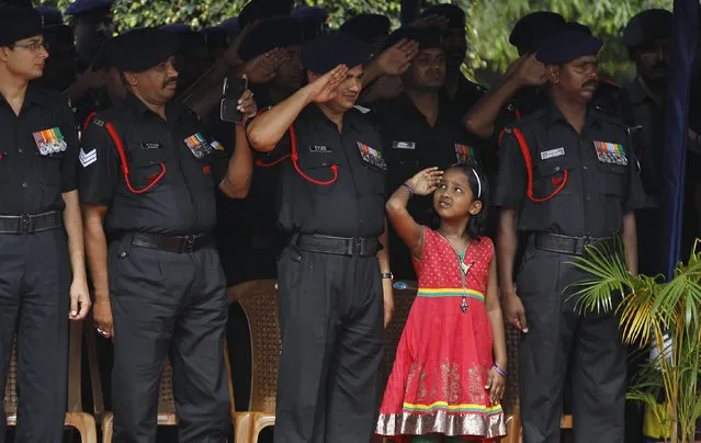 A girl next to indian army soldiers salute the national flag during a graduation ceremonial parade of newly inducted Indian army personnel in Bangalore, India, Friday, August 12, 2016. A total of 240 recruits were inducted into the Indian army Friday. The Indian army is the world's third largest army with more than 1.3 million active troops. (Photo by Aijaz Rahi/AP Photo)
