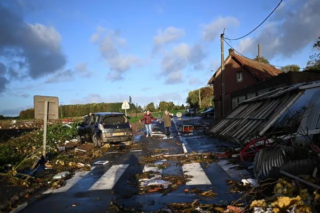Local residents walk past damages in Bihucourt, northern France, on October 24, 2022 after a tornado hit the region. (Photo by Sameer Al-Doumy/AFP Photo)