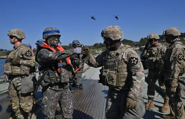 A South Korean soldier (2nd L) reacts with a US soldier (3rd R) as they set up a floating bridge during a South Korea-US joint river-crossing drill as part of the annual Hoguk military exercise in Yeoju on October 19, 2022. (Photo by Jung Yeon-je/AFP Photo)