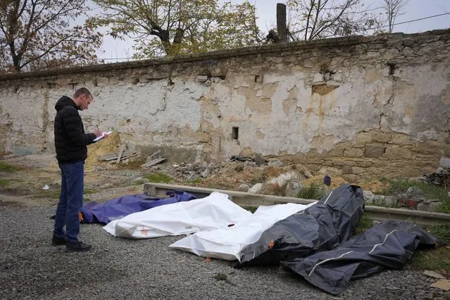 A criminologist examines bodies of civilians after a Russian shelling, at a city morgue in Mykolayiv, Ukraine, Saturday, November 12, 2022. (Photo by Efrem Lukatsky/AP Photo)