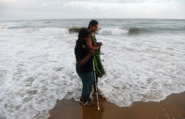 An Indian volunteer helps a visually impaired girl to take a walk at Elliot's beach in Chennai on December 3, 2017. People with disabilities were taken to the beach by volunteers on the occasion of International Day of Disabled Persons. (Photo by Arun Sankar/AFP Photo)