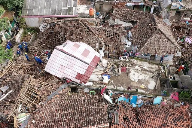 An aerial view shows rescue personnel working to rescue a child from the rubble of a collapsed house at Cugenang in Cianjur, West Java on November 24, 2022, following a 5.6-magnitude earthquake on November 21. Survivors of an Indonesian earthquake that killed at least 271 people, many of them children, appealed for food and water November 23 as heavy rain and aftershocks hampered rescue efforts among the rubble of devastated villages. (Photo by Adek Berry/AFP Photo)