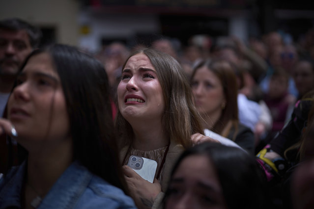 A woman reacts in tears as she looks at the figure of Christ being carried out of the church of the brotherhood of El Cerro, during Holy Week in Seville, Spain, Tuesday, April 15, 2025. (Photo by Emilio Morenatti/AP Photo)