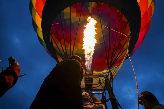 Attendees watch a hot air balloon gets lit by flames as it is being prepared for take off during the 2015 Albuquerque International Balloon Fiesta in Albuquerque, New Mexico, October 4, 2015. (Photo by Lucas Jackson/Reuters)