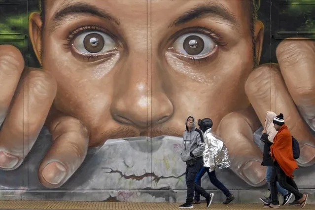 A group of migrants in central Calais walk past a mural by artist Braga Last One on November 05, 2022 in Calais, France. Around 2,000 migrants are reportedly living in northern France, many sleeping rough scattered around the Calais and Dunkirk area, as they wait to cross the English Channel on board small boats or smuggled in lorries. (Photo by Christopher Furlong/Getty Images)