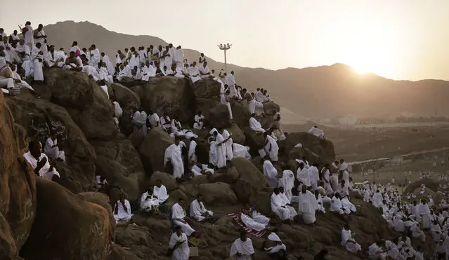 Muslim pilgrims pray on a rocky hill known as Mountain of Mercy, on the Plain of Arafat, during the annual hajj pilgrimage, ahead of sunrise near the holy city of Mecca, Saudi Arabia, Sunday, September 11, 2016. Mount Arafat, marked by a white pillar, is where Islam's Prophet Muhammad is believed to have delivered his last sermon to tens of thousands of followers some 1,400 years ago, calling on Muslims to unite. (Photo by Nariman El-Mofty/AP Photo)