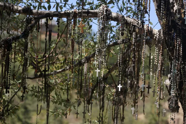 Rosaries hang on a tree at the Christian memorial of Our Lady of Elije (Elige) on September 18, 2016 in the northern Lebanese village of Mayfouk as members of the Lebanese Christian community held a mass commemorating Christian fighters and members of the clergy killed during Lebanon's civil war. (Photo by Patrick Baz/AFP Photo)