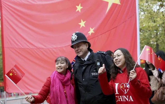 Supporters of China's President Xi Jinping pose for a photo with a police officer as they wait on the Mall for him to pass during his ceremonial welcome, in London, Britain, October 20, 2015. (Photo by Neil Hall/Reuters)