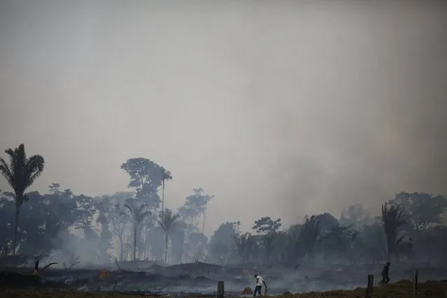 Men try to extinguish a fire at a farm in Rio Pardo next to Bom Futuro National Forest, in the district of Porto Velho, Rondonia State, Brazil, August 30, 2015. (Photo by Nacho Doce/Reuters)