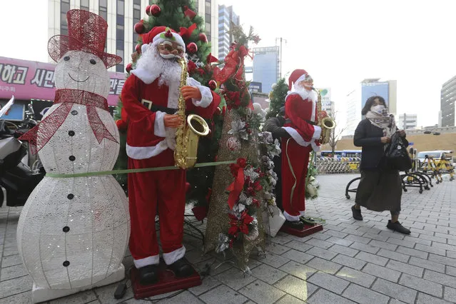 A woman wearing a face mask as a precaution against the coronavirus passes by Christmas decorations outside a shopping mall in Seoul, South Korea, Friday, November 27, 2020. South Korea's daily virus tally hovered above 500 for the second straight day, as the country's prime minister urged the public to stay home this weekend to contain a viral resurgence. (Photo by Ahn Young-joon/AP Photo)