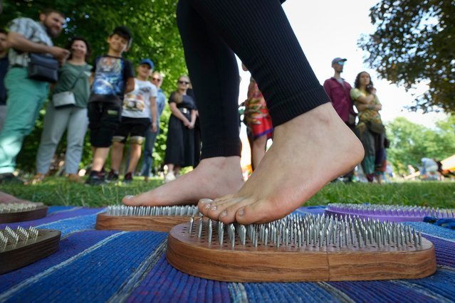 A girl walks on a planks with nails during an Indian festival dedicated to upcoming International Yoga Day in a park in St. Petersburg, Russia, Sunday, June 16, 2024. (Photo by Dmitri Lovetsky/AP Photo)