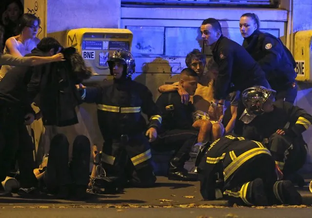 French fire brigade members aid an injured individual near the Bataclan concert hall following fatal shootings in Paris, France, November 13, 2015. (Photo by Christian Hartmann/Reuters)