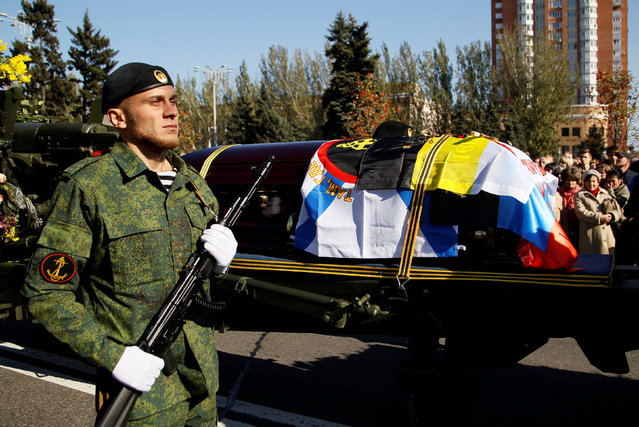 A member of self-proclaimed Donetsk People's Republic forces walks next to the coffin of Russian separatist commander Arseny Pavlov, known by the nom de guerre “Motorola”, who was blown up in the lift of his apartment building on October 16, during his funeral ceremony in Donetsk, Ukraine, October 19, 2016. (Photo by Alexander Ermochenko/Reuters)