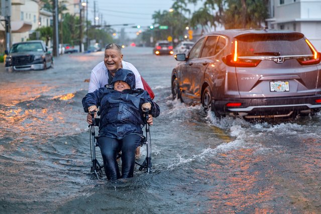Victor Corone, 66, pushes his wife Maria Diaz, 64, in a wheelchair through more than a foot of flood water on 84th street in Miami Beach, Fla. on Wednesday, June 12, 2024. The annual rainy season has arrived with a wallop in much of Florida, where a disorganized disturbance of tropical weather from the Gulf of Mexico has caused street flooding and triggered tornado watches but so far has not caused major damage or injuries. (Photo by A.L. Diaz/Miami Herald via AP Photo)