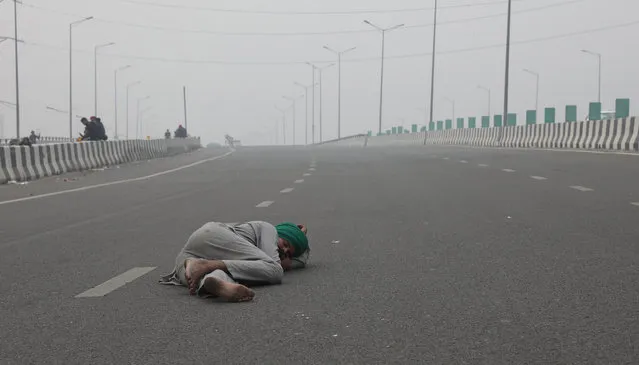 An Indian farmer sleeps on a highway as he takes part in a protest against new farm laws at Delhi-Uttar Pradesh border, India, 12 December 2020. Thousands of farmers gathered and tried to cross the sealed New Delhi border points to hold protests against the government's farm laws. Farmers were stopped by the police at the various points outside Delhi border which are connected with neighboring states of Haryana and Uttar Pradesh. (Photo by Rajat Gupta/EPA/EFE)