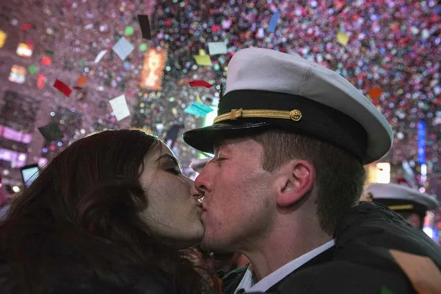 A couple kisses amid confetti as the clock strikes midnight during New Year's Eve celebrations in Times Square, New York January 1, 2015. (Photo by Stephanie Keith/Reuters)