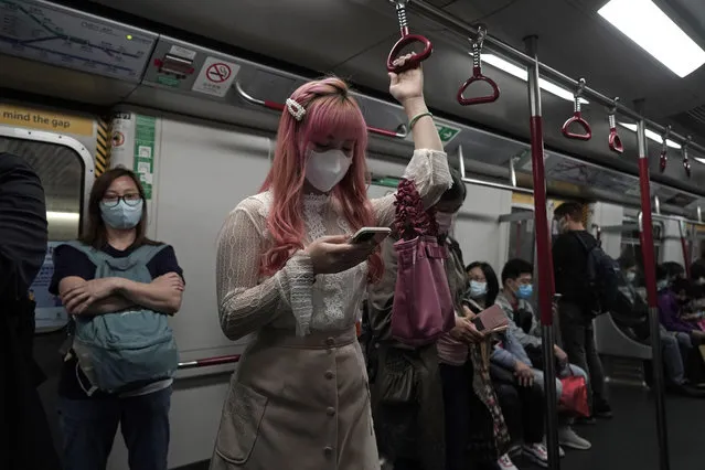 A woman wearing a face mask as a precaution against the COVID-19 while using smartphone in a subway train in Hong Kong, Thursday, February 27, 2020. As the worst-hit areas of Asia continued to struggle with a viral epidemic, with hundreds more cases reported Thursday in South Korea and China, worries about infection and containment spread across the globe. (Photo by Kin Cheung/AP Photo)