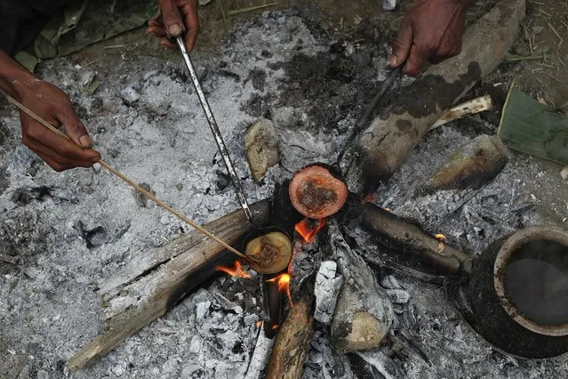 Naga men cook raw opium as they prepare it for smoking at a hunter's base in an opium field during a hunting trip between Donhe and Lahe township in the Naga Self-Administered Zone in northwest Myanmar December 27, 2014. The opium is spread on cloth to dry and then heated with water. (Photo by Soe Zeya Tun/Reuters)