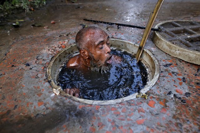 The workers are sent down into the sludge to clear the sewers in the Bangladeshi capital Dhaka on May 23, 2018. Heavy rains have worsened the sewage situation in the city. (Photo by Rehman Asad/Barcroft Media)