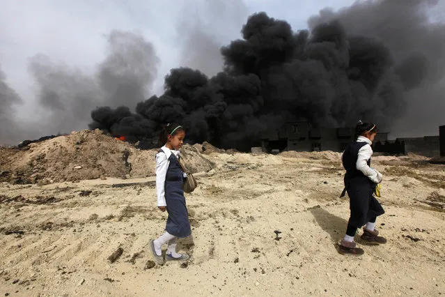 Girls walk as smoke rises from oil wells, set ablaze by Islamic State militants before IS militants fled the oil-producing region of Qayyara, Iraq, November 1, 2016. (Photo by Alaa Al-Marjani/Reuters)
