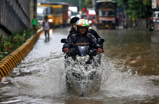 A man rides a motorcycle through a water-logged street after heavy rains in Mumbai, June 9, 2018. (Photo by Francis Mascarenhas/Reuters)