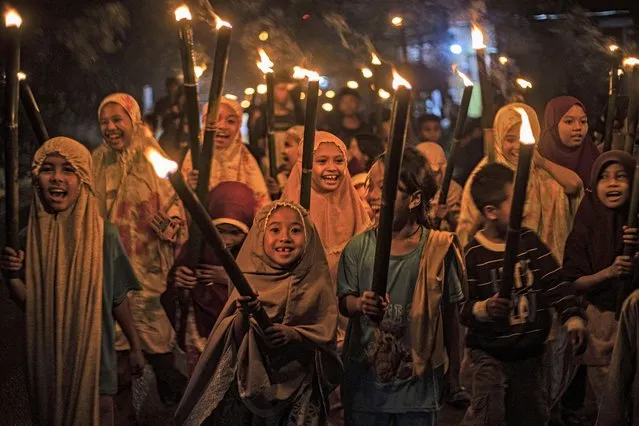 Muslim girls carry torches as they parade to celebrate the eve of Eid al-Fitr, the holiday marking the end of the holy fasting month of Ramadan, in Polewali Mandar, West Sulawesi, Indonesia, Friday, April 21, 2023. (Photo by Yusuf Wahil/AP Photo)