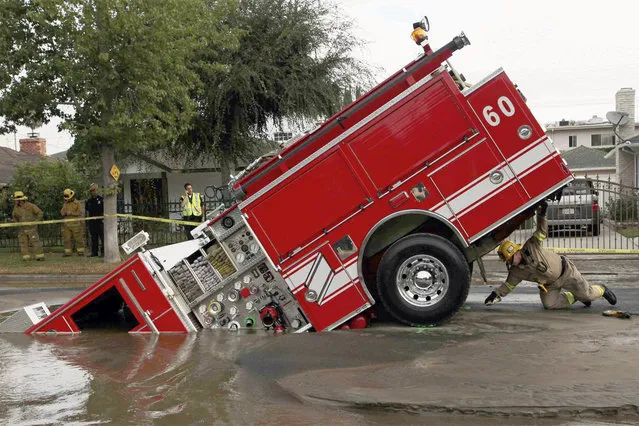 A Los Angeles fireman looks under a fire truck stuck in a sinkhole in the Valley Village neighborhood of Los Angeles, on September 8, 2009. Four firefighters escaped injury early Tuesday after their fire engine sunk into a large hole caused by a burst water main in the San Fernando Valley, authorities said. (Photo by Nick Ut/AP Photo via The Atlantic)