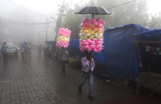 Traveling vendors selling cotton-candy walk in the fog in Dharmsala, India, Monday, July 9, 2018. (Photo by Ashwini Bhatia/AP Photo)