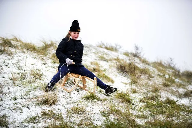 A girl sits on a sledge with little snow in Zandvoort, Netherlands, 16 January 2021. In some parts on the country snow fell around three centimeters high. (Photo by Remko de Waal/EPA/EFE)