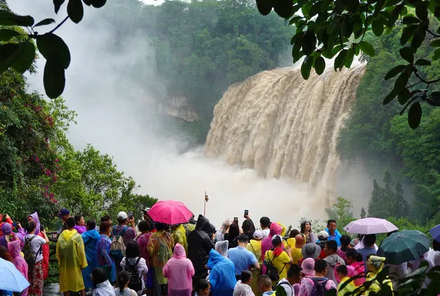 Tourists visit Huangguoshu Waterfall scenic spot in the rain on July 4, 2023 in Anshun, Guizhou Province of China. Huangguoshu Waterfall has entered its high flow season due to sustained rainfalls in summer. (Photo by Qin Gang/VCG via Getty Images)