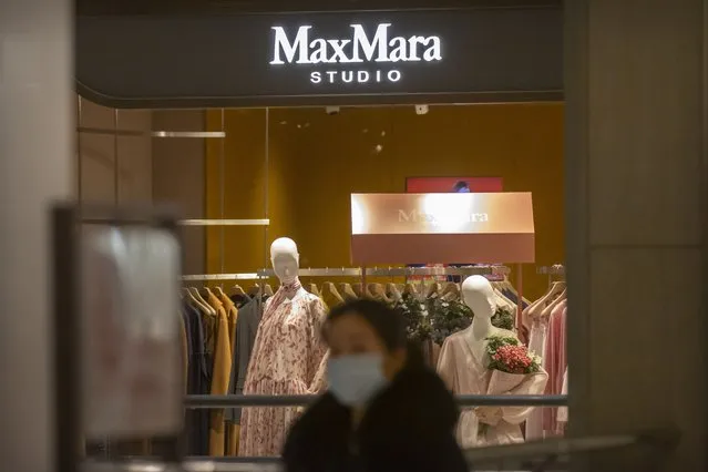 A shopper walks past a MaxMara clothing store at an upscale shopping mall in Beijing, Tuesday, March 16, 2021. Chinese state TV has criticized bathroom fixtures brand Kohler, automaker BMW and MaxMara fashion boutiques for using facial recognition to identify customers in a possible violation of privacy rules that took effect this year. (Photo by Mark Schiefelbein/AP Photo)
