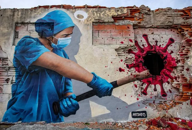 A street art mural entitled “Angels On Earth”, depicts nurse Sofia hitting a Coronavirus molecule with a baseball bat on February 24, 2021 in Vila Nova de Gaia, Portugal. The mural by street artist Mr. Dheo pays tribute to Portuguese nurse Sofia from São João Hospital, who was infected with Covid-19 and nevertheless returned to the hospital's front line of the pandemic. (Photo by Octavio Passos/Getty Images)