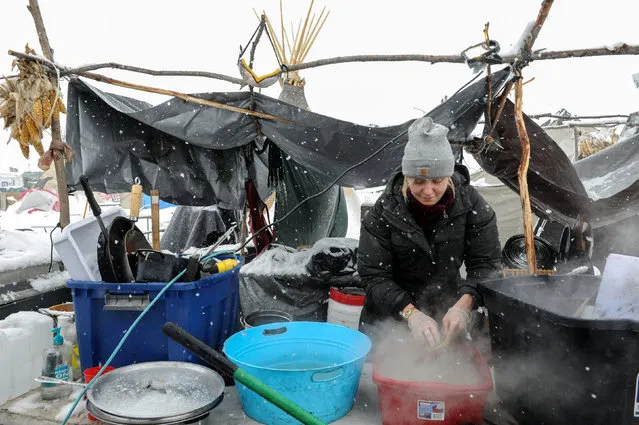 A woman washes dishes in the Oceti Sakowin camp in a snow storm during a protest against plans to pass the Dakota Access pipeline near the Standing Rock Indian Reservation, near Cannon Ball, North Dakota, U.S. November 28, 2016. (Photo by Stephanie Keith/Reuters)