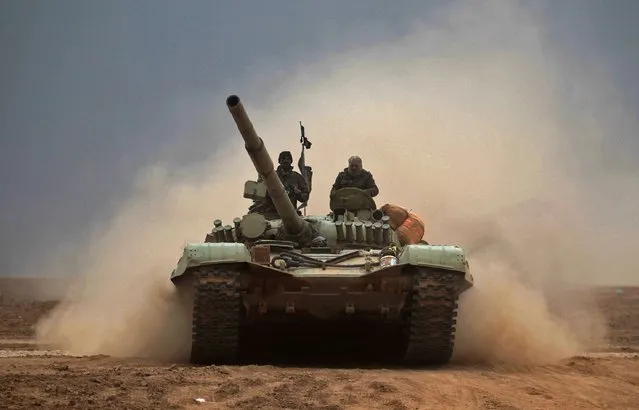 Iraqi Shiite fighters from the Hashed al- Shaabi (Popular Mobilisation) paramilitaries drive a T-72 tank as they advance near the village of Tal Abtah, south of Tal Afar, on November 30, 2016 during a broad offensive by Iraq forces to retake the city Mosul from jihadists of the Islamic State group. (Photo by Ahmad Al- Rubaye/AFP Photo)