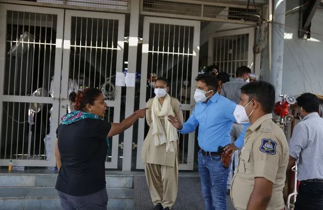 A relative of a patient argues with a police officer outside a government COVID-19 hospital in Ahmedabad, India, Tuesday, April 27, 2021. (Photo by Ajit Solanki/AP Photo)