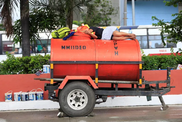 A worker takes a break atop of a water tank parked along a main street in metro Manila, Philippines September 28, 2016. (Photo by Romeo Ranoco/Reuters)