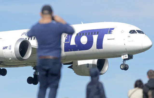 In this September 30, 2018 photo people watch a landing Polish Airlines LOT jetliner at the Chopin airport in Warsaw, Poland. Poland's national airline LOT is cancelling some flights since Oct. 22, 2018, as some crew members don't show up for work as they are striking to protest layoffs and demand better working conditions. (Photo bt Alik Keplicz/AP Photo)