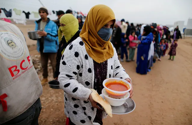A woman who fled the Islamic State stronghold of Mosul, receives food at a refugee camp, Iraq,December 18, 2016. (Photo by Ammar Awad/Reuters)