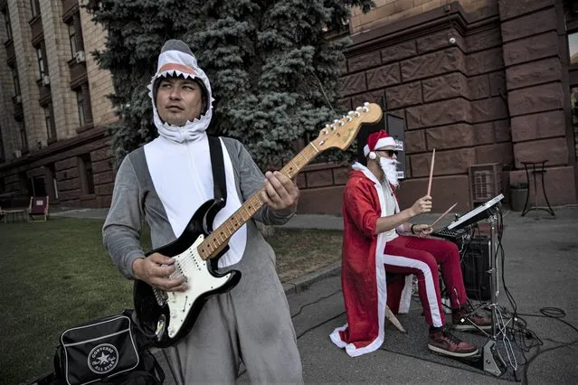 Street musicians, wearing customs of Santa Claus and a shark, perform on Dmitra Yahorntsko Avenue in Ukraine's Dnipro, which is nearly 300km away from heavy clashes, to earn their living on July 07, 2022. Employment decreased due to the war in Ukraine as citizens struggle to earn their living. (Photo by Metin Aktas/Anadolu Agency via Getty Images)