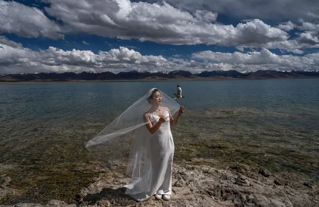 A woman has her wedding photos taken on the shore of the high altitude saltwater Namtso lake during a government organized visit for journalists on June 2, 2021 in Namtso, Tibet Autonomous Region, China. Travel restrictions for foreign travellers were recently loosened in a bid to boost tourism to Tibet. Chinas government is aiming for 61 million visitors annually by 2025, more than 15 times the number of Tibets inhabitants. Foreign journalists, normally not permitted to travel to the autonomous region, were recently taken on a government-organized visit. (Photo by Kevin Frayer/Getty Images)