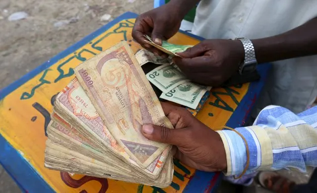 A dealer counts of Somalian currency (shillings) and U.S. dollars at an open forex bureau along Hamarweyne district of in Somalia's capital Mogadishu, January 27, 2016. (Photo by Feisal Omar/Reuters)
